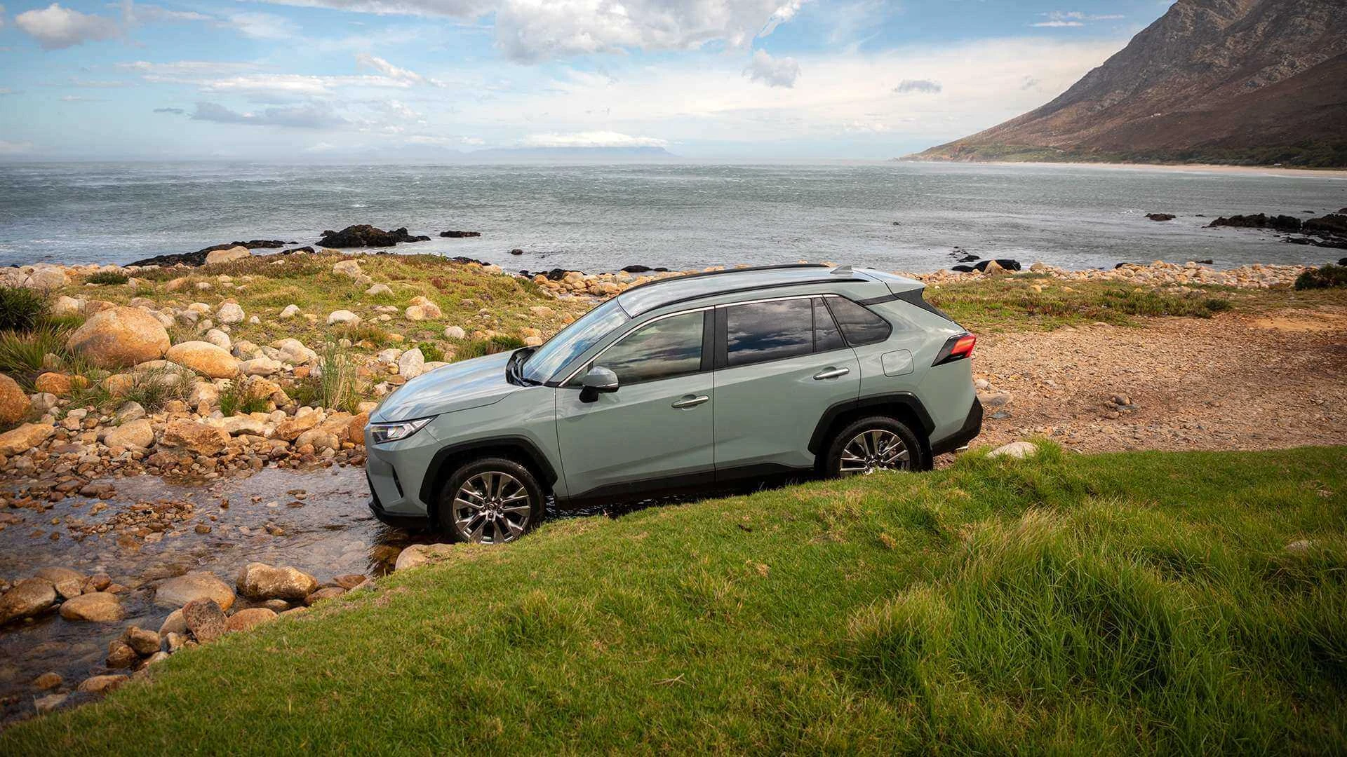 An image of Toyota RAV 4 driving on rocky terrain with water